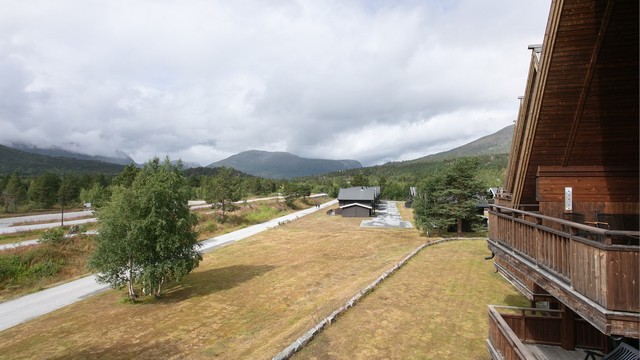 Åpent utsyn mot grøntarealer og fjelltoppene rundt dalen.