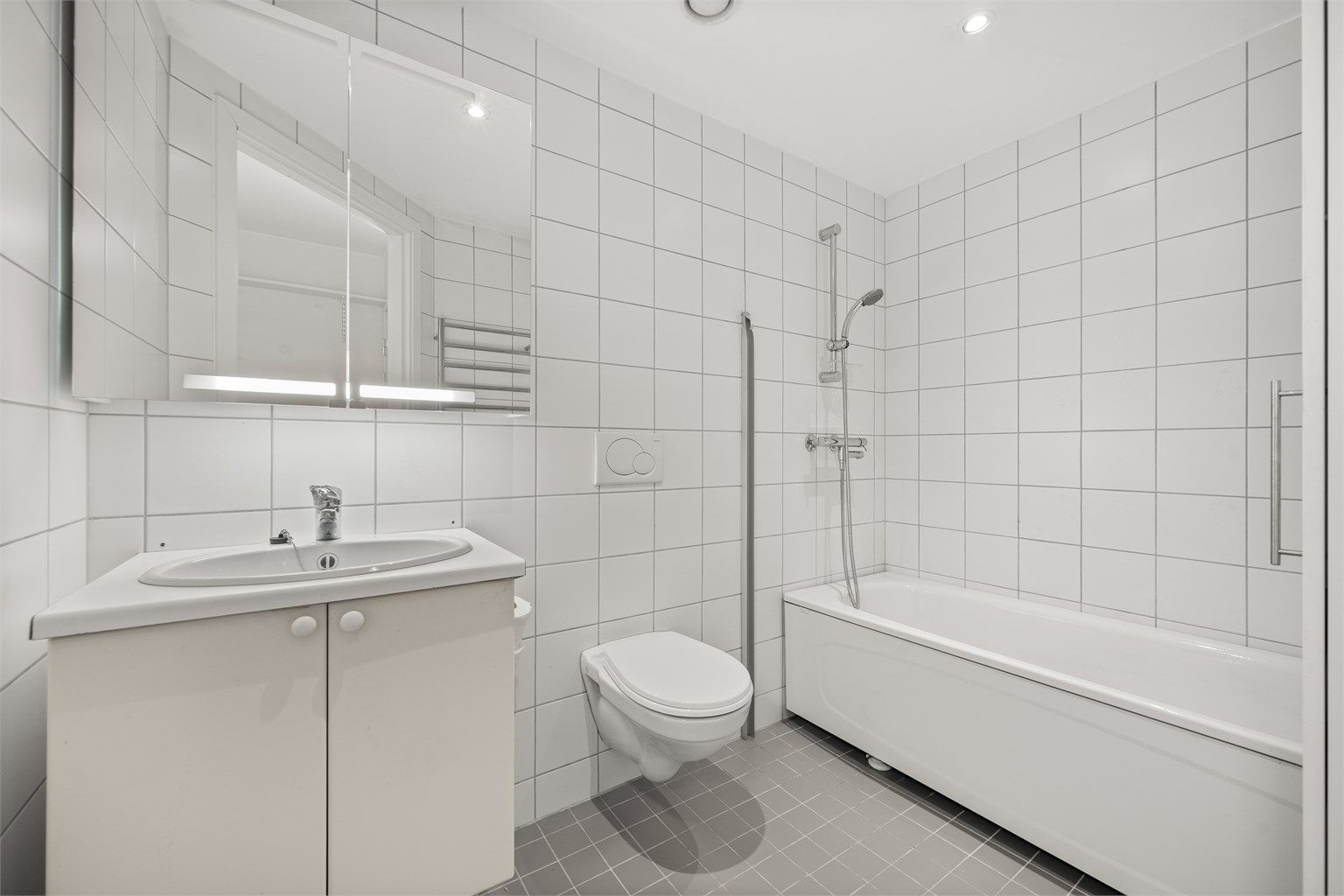 Leilighetens andre bad er også flislagt med elektrisk gulvvarme og er innredet med badekar. Badet har servant nedfelt i innredning, speilskap med belysning, vegghengt håndklevarmer og vegghengt klosett.