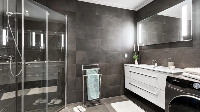 Pent flislagt bad med gulvvarme. Himling med downlights. Dusjhjørne med nedsenket gulv med dører i glass.