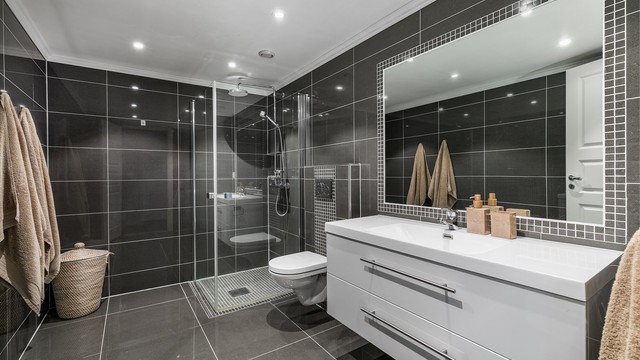 Det store badet ble også ekstra påkostet da leiligheten ble oppført. Grå fliser på gulv og vegger skaper helhet.