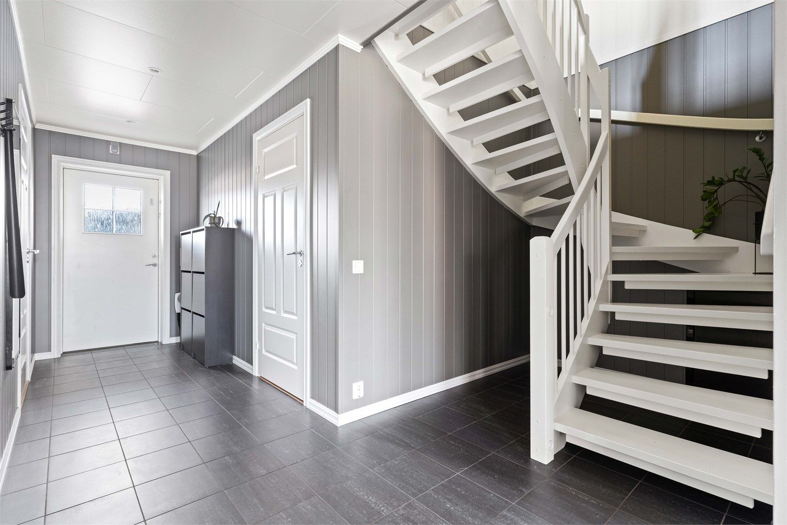 Velkommen inn i en romslig entré med flislagt gulv og behagelig gulvvarme.