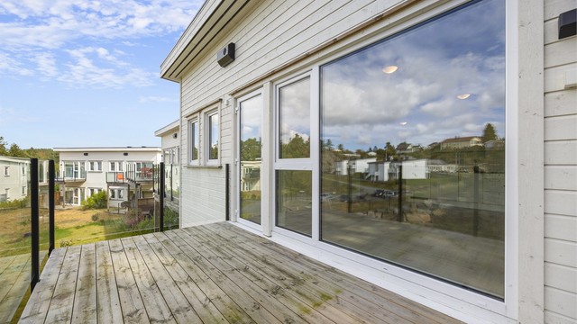 Balkongen er utført i behandlet tre med glassrekkverk og har plass til sittegruppe.