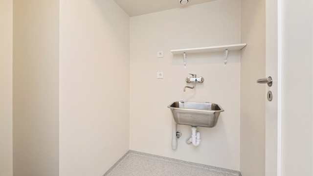 Praktisk vaskerom med gulvvarme, utslagsvask og opplegg for vaskemaskin.
