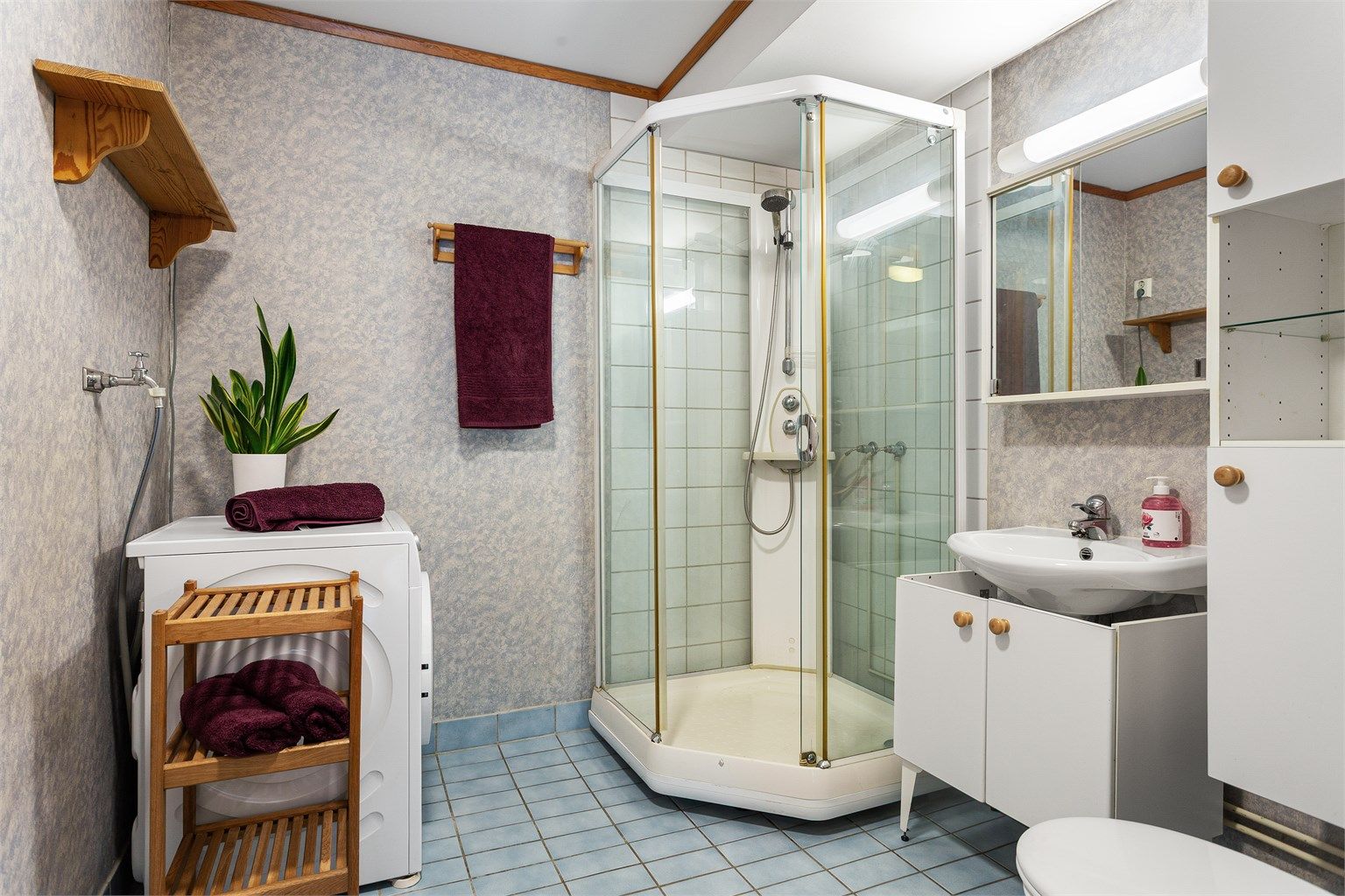 Badet har flislagt gulv med gulvvarme og det er praktisk opplegg for vaskemaskin.