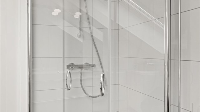 Dusjhjørnet har innfellbare glassdører som frigjør gulvplass når dusjen ikke er i bruk.