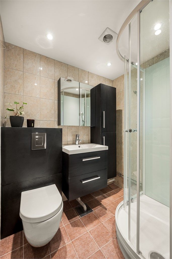 Badet er flislagt og utstyrt med vegghengt toalett og servantinnredning.