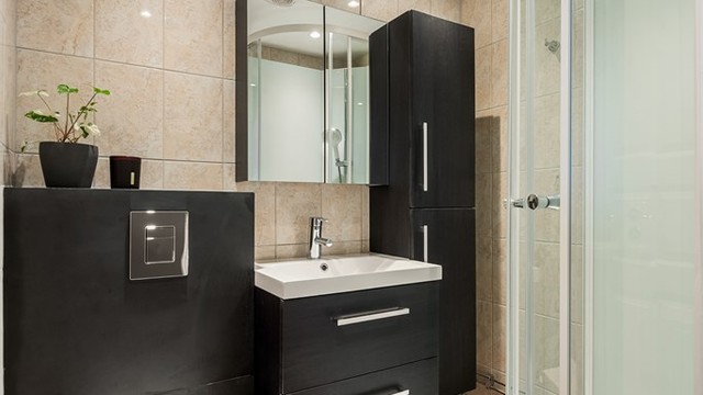 Badet er flislagt og utstyrt med vegghengt toalett og servantinnredning.