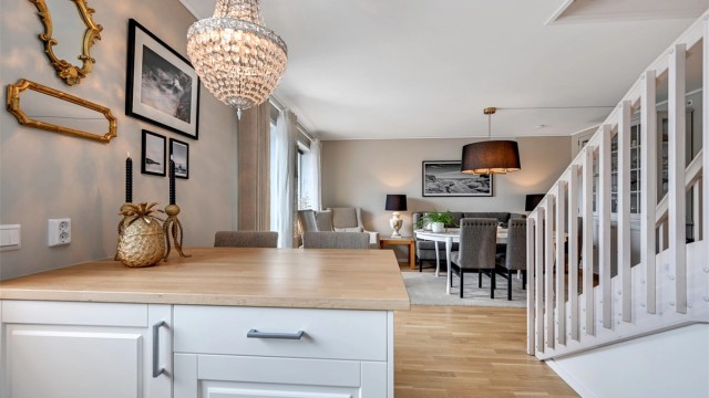 Mellom kjøkken og stue er det etablert en praktisk kjøkkenøy som gir et naturlig skille i rommet, samtidig som den byr på ekstra benkeplass, skuffer og skap – og fungerer utmerket som en hyggelig frokostplass.