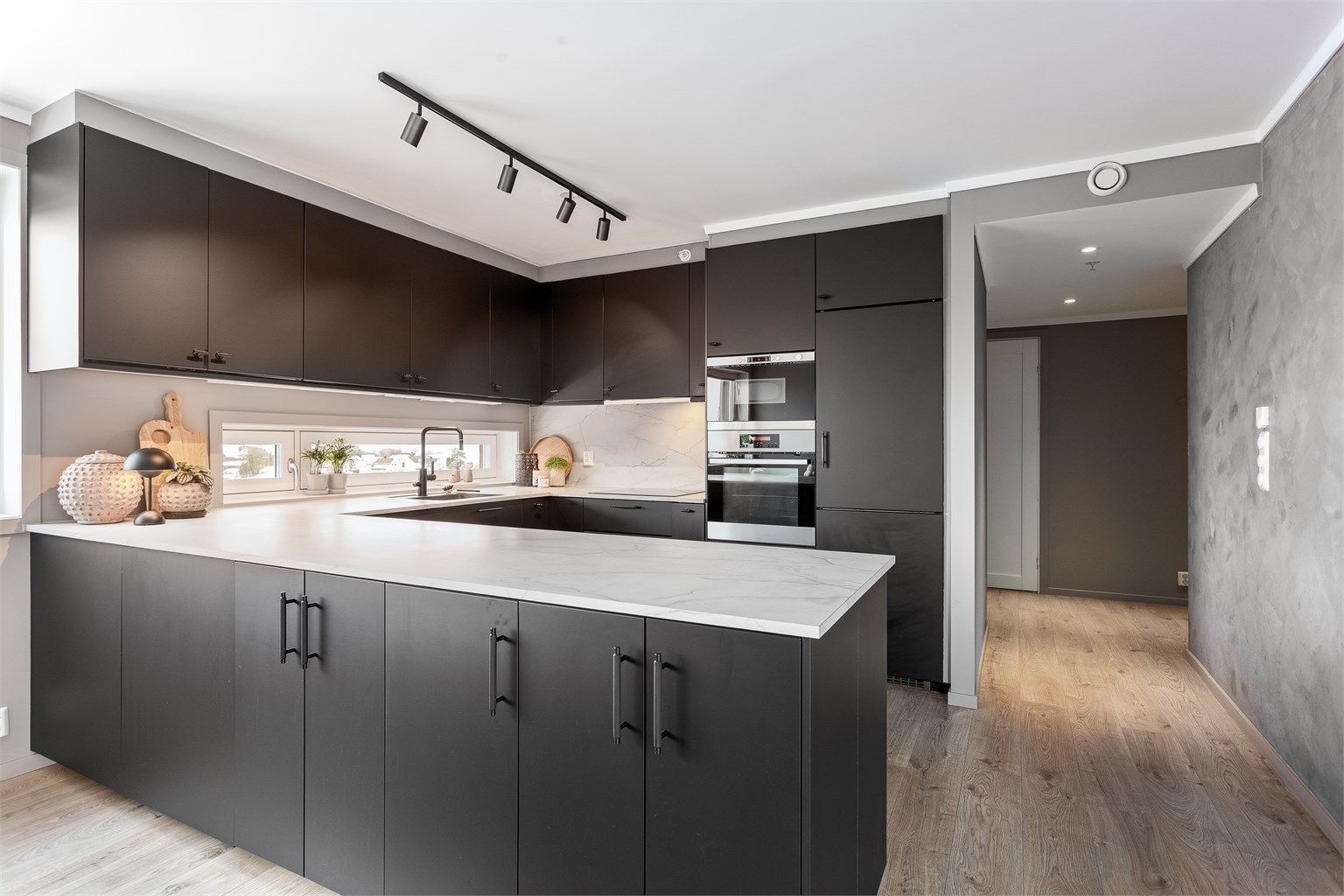 Pent kjøkken med IKEA innredning med glatte fronter. Benkeplate med laminert overflate og kjøkkenvask og kum.