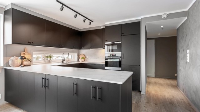 Pent kjøkken med IKEA innredning med glatte fronter. Benkeplate med laminert overflate og kjøkkenvask og kum.