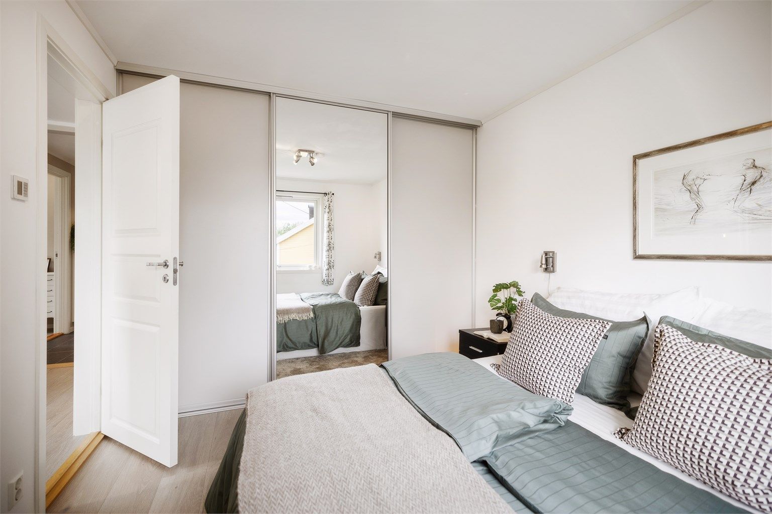 Stor skyvedørsgarderobe gir rikelig med oppbevaringsplass og bidrar til et ryddig og stilrent soverom.