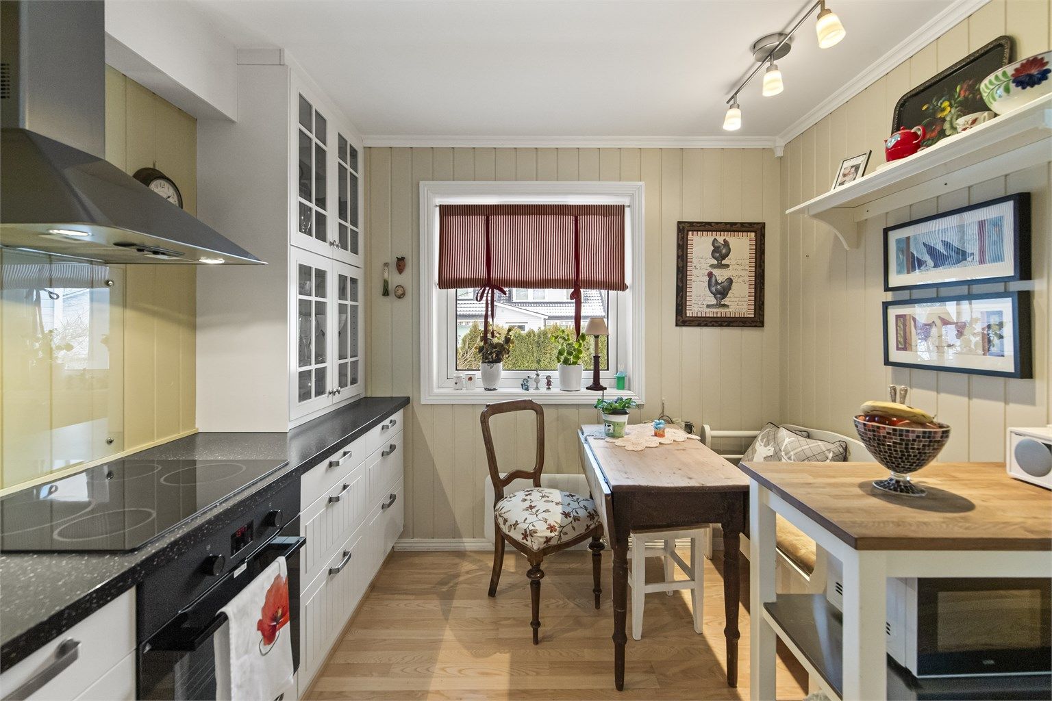 Lyst og trivelig kjøkken med pene gulv og malt panel på vegg