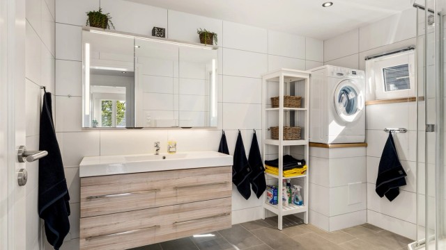 Badet har samme overlate og farge som gulvflisene i entrén, men her er det rektangulære, noe som bidrar til at rommet virker større.