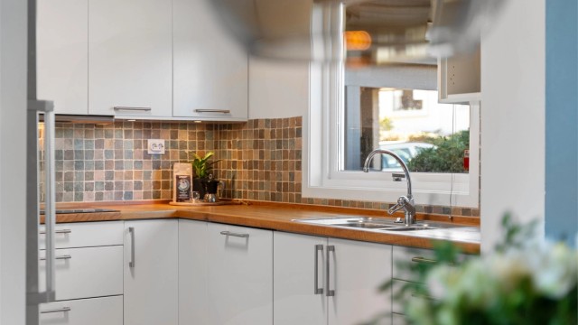 Fliser på vegg mellom overskap og benk, i tillegg til stort vindu over benk som gir lysinnslipp og utsikt mot terrasse og inngangsparti.