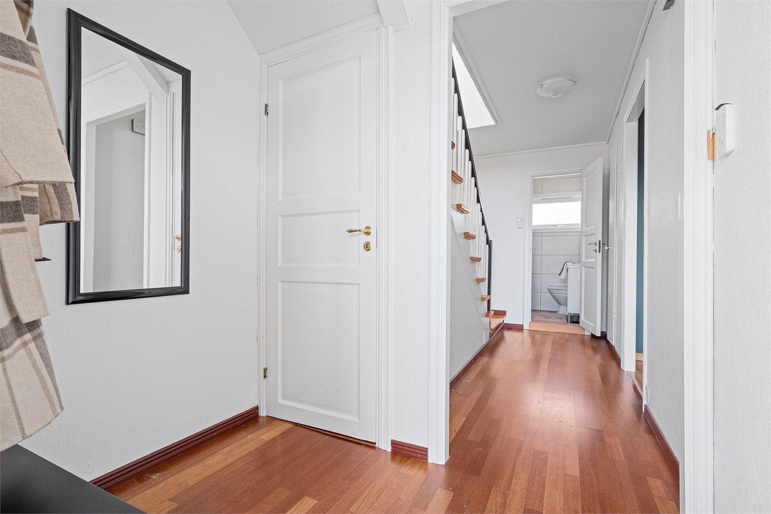 Vindfang med plass til å sette av sko og henge av yttertøy. Videre kommer man inn til gang og trapp opp til 2.etg. 
Lysmalte vegger. Det er trapp ned til kjeller fra vindfang. 