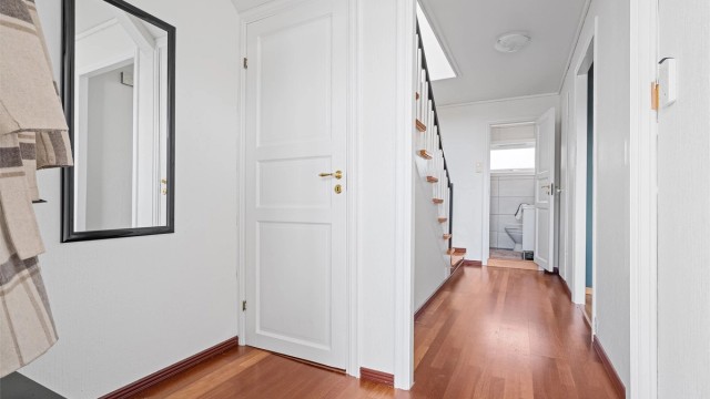 Vindfang med plass til å sette av sko og henge av yttertøy. Videre kommer man inn til gang og trapp opp til 2.etg.
Lysmalte vegger. Det er trapp ned til kjeller fra vindfang.