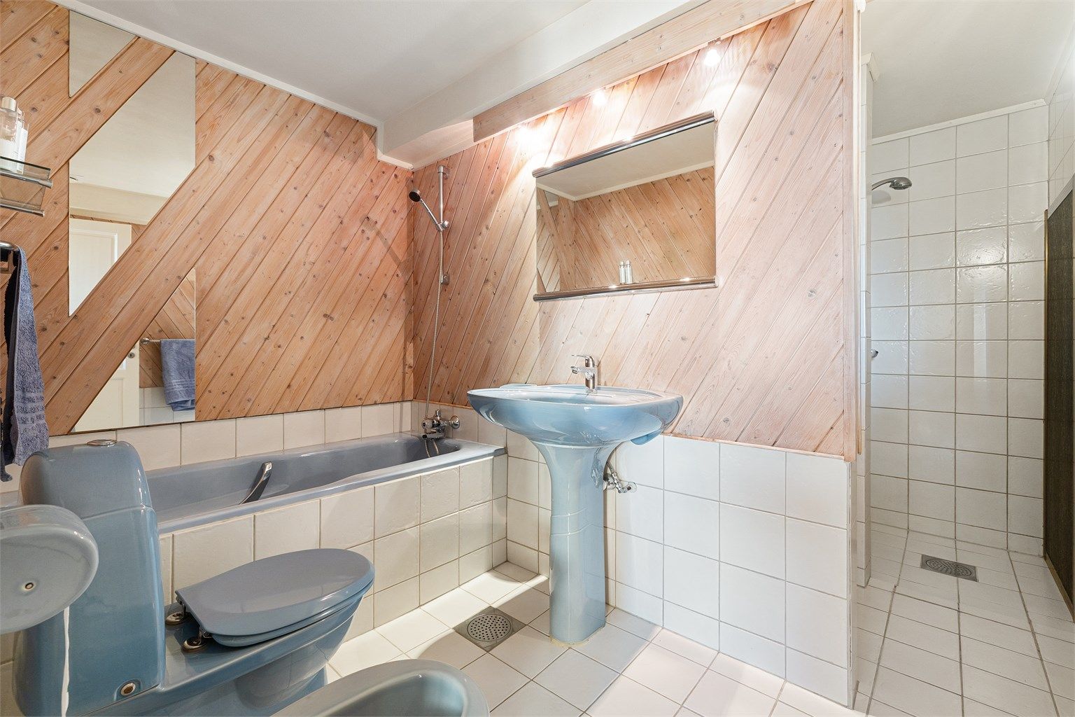 Funksjonelt innredet baderom fra byggeår med servant, speil med belysning, gulvstående toalett og bidé, innbygd badekar og dusjhjørne. Rommet har avtrekksventil i himlingen.