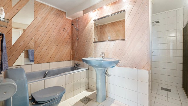 Funksjonelt innredet baderom fra byggeår med servant, speil med belysning, gulvstående toalett og bidé, innbygd badekar og dusjhjørne. Rommet har avtrekksventil i himlingen.