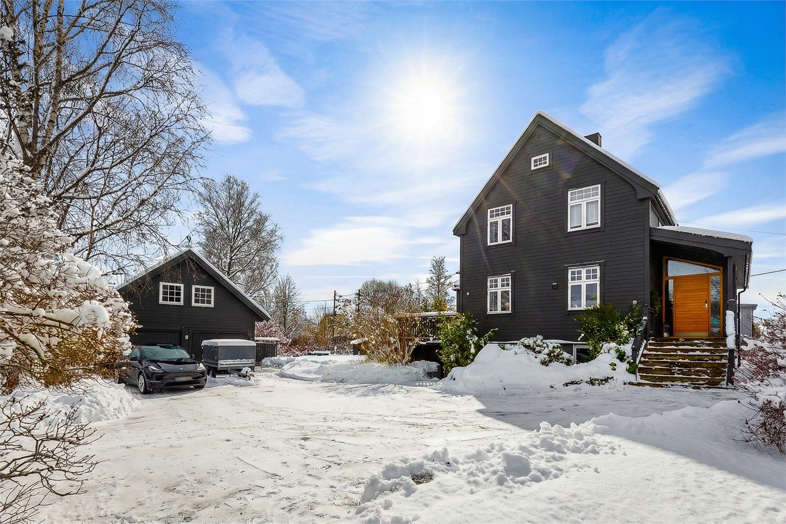 En betydelig påkostet enebolig med stor, separat garasjebygning.