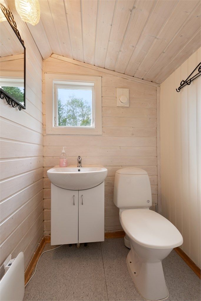 Toalettrommet har gulvbelegg og malt panel på veggene
