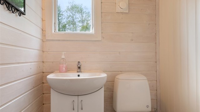 Toalettrommet har gulvbelegg og malt panel på veggene