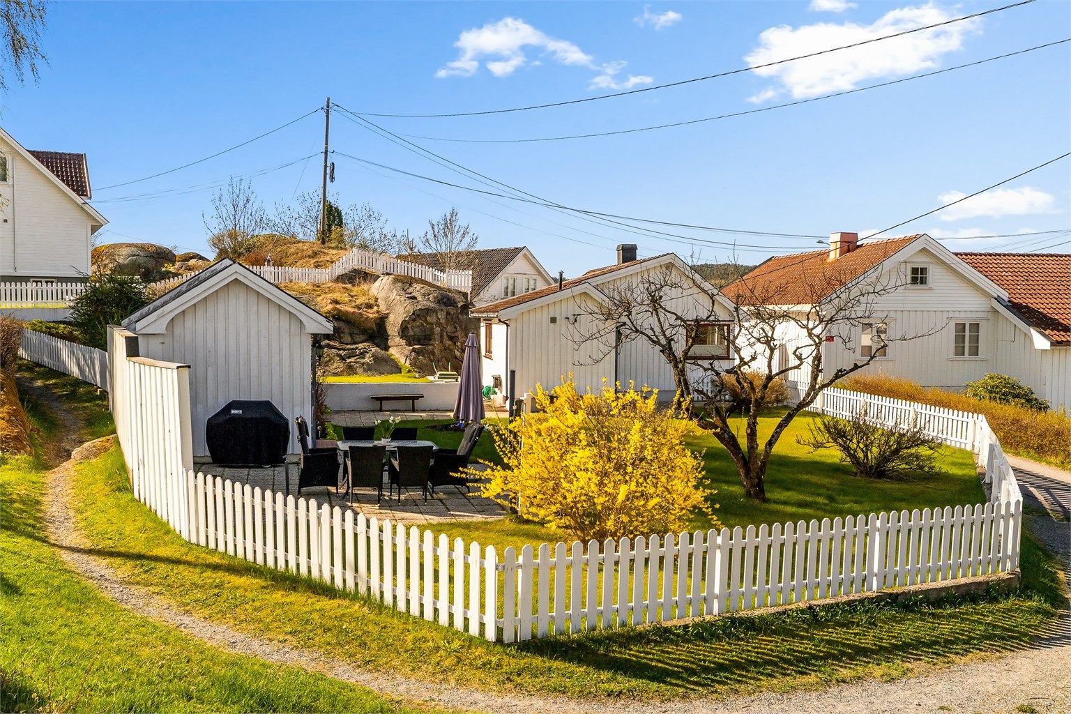 Hagen er inngjerdet og beplantet med fruktre, prydbusker og blomsterbed.