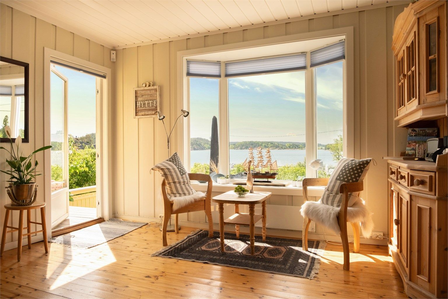 Moderne, toppmonterte plisségardiner fra Markisemannen er i senere år installert både i stuen og på kjøkkenet.