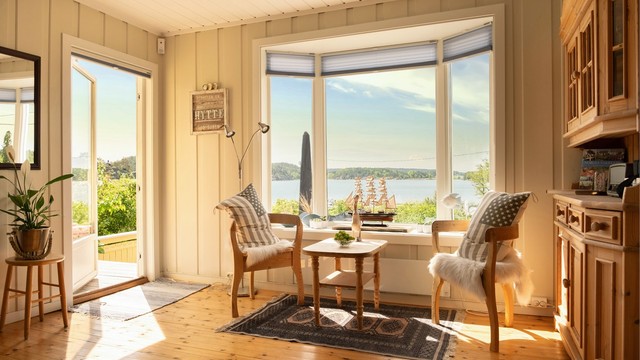 Moderne, toppmonterte plisségardiner fra Markisemannen er i senere år installert både i stuen og på kjøkkenet.