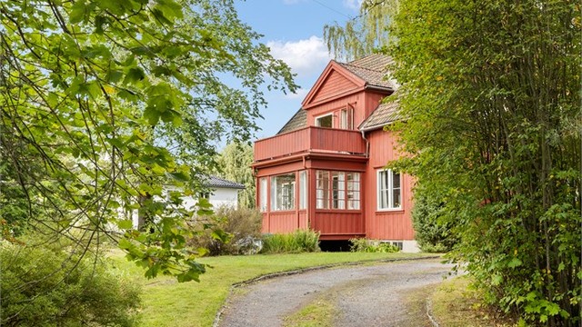 Eiendommen ligger skjermet fra veien, omgitt av frodig vegetasjon.