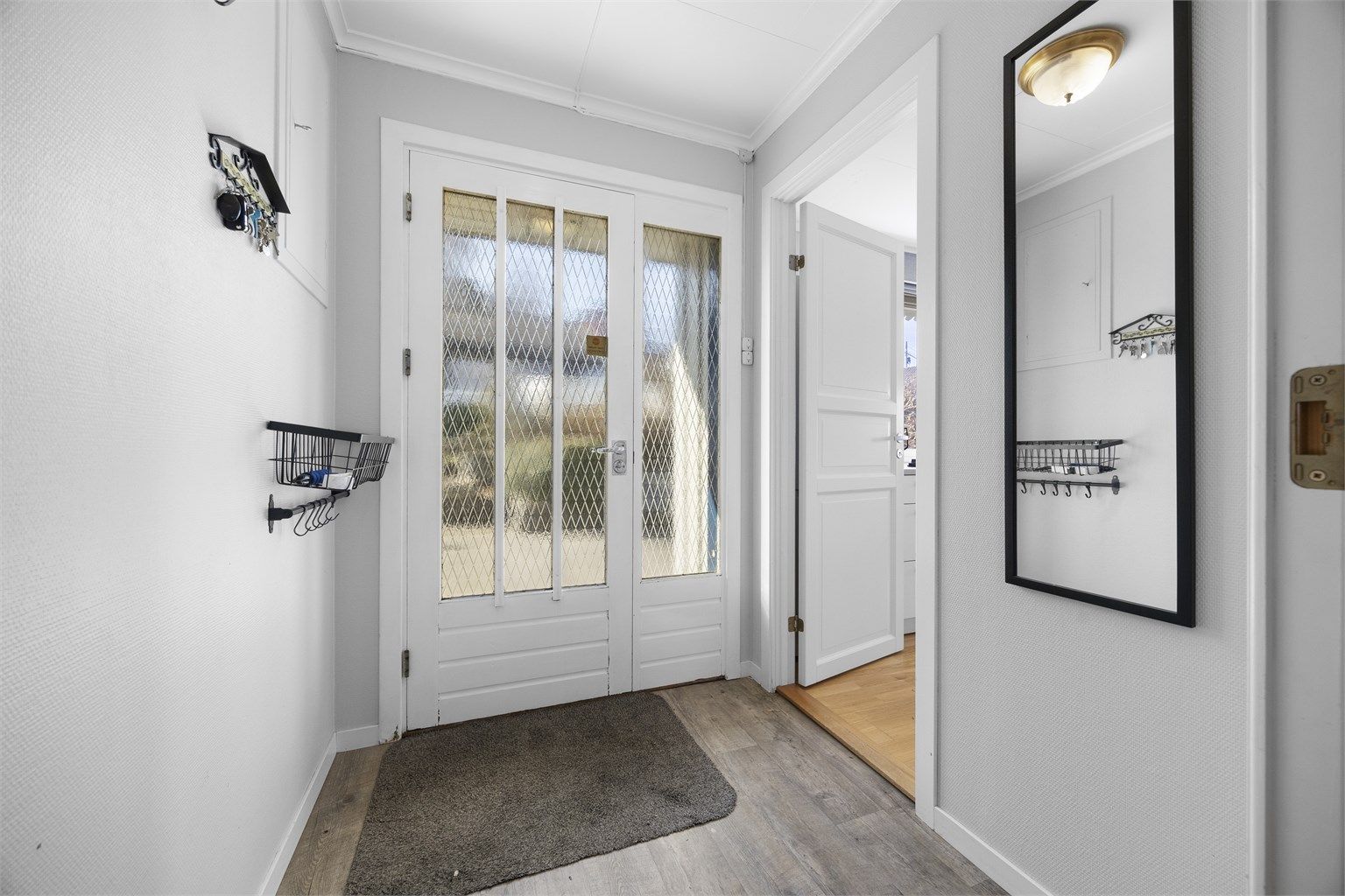 Vindfanget ønsker velkommen inn i boligens hovedetasje. Innerdøren med glassfelt gir et fint lysinnslipp til gangen.