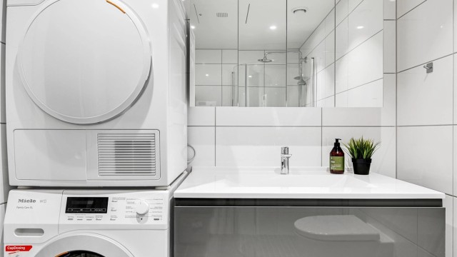 Dette badet inneholder servant i baderomsinnredningen, veggmontert toalett, dusjhjøne med dusjvegger, samt opplegg for vaskemaskin/tørketrommel.