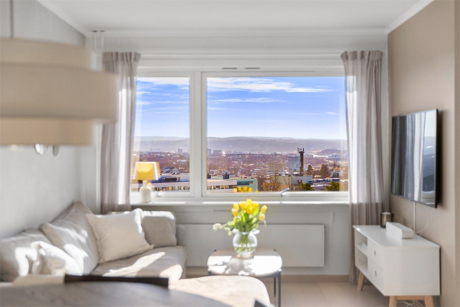 Stuen har god plass til både sofagruppe, spisebord og vitrineskap. Flott utsikt utover Oslo by og fjord