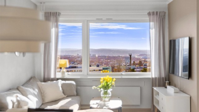 Stuen har god plass til både sofagruppe, spisebord og vitrineskap. Flott utsikt utover Oslo by og fjord