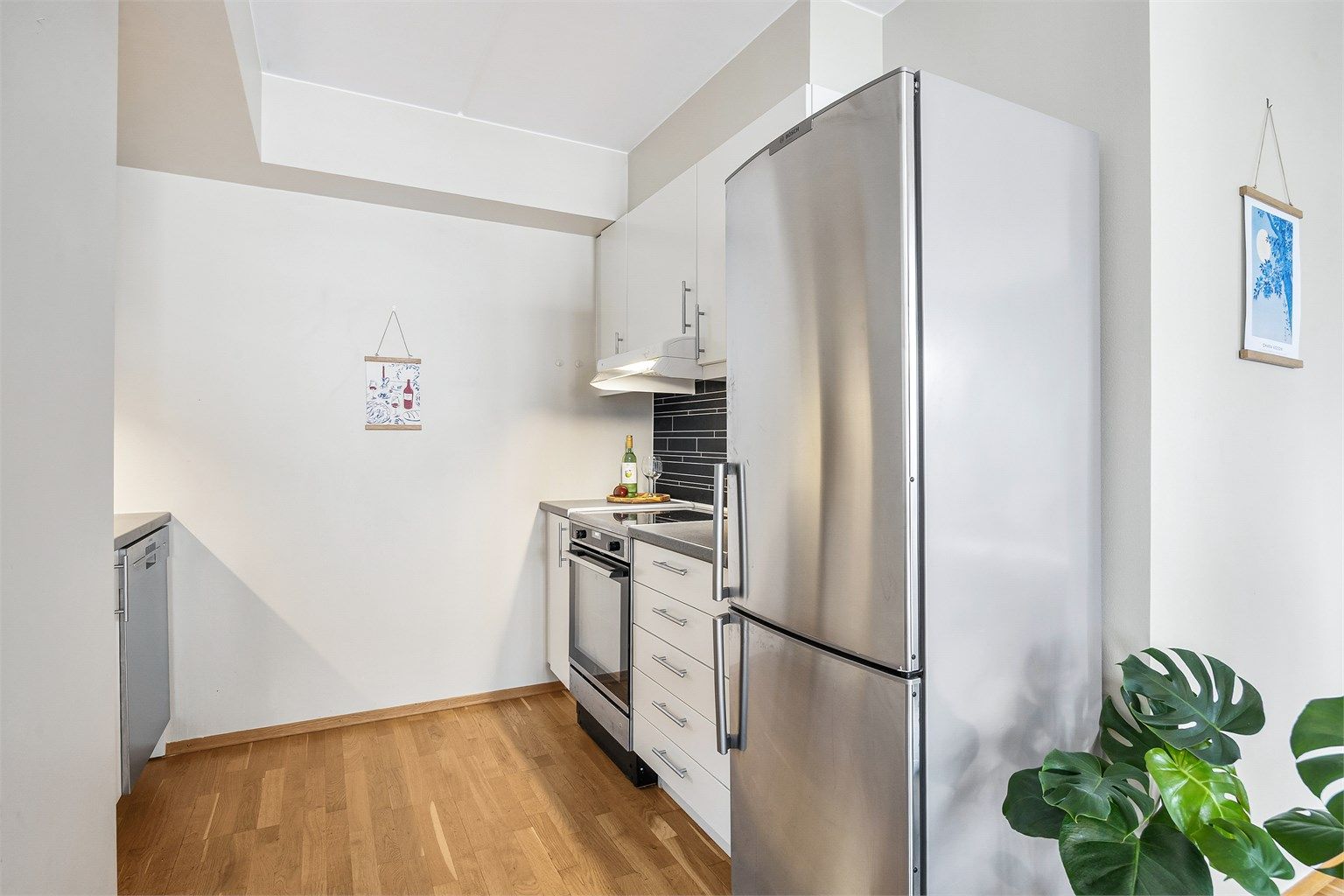 Kjøkkeninnredning med lyse, glatte fronter og benkeplate med laminert overflate.