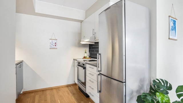 Kjøkkeninnredning med lyse, glatte fronter og benkeplate med laminert overflate.