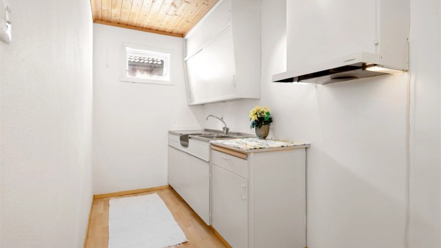 Kjøkkenet i underetasjen er en del av hybelen. Innredningen er enkel med malte fronter og laminatbenkeplate.