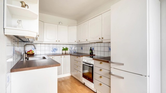 Kjøkkeninnredning med profilerte fronter, laminatbenkeplate og fliser over benken.