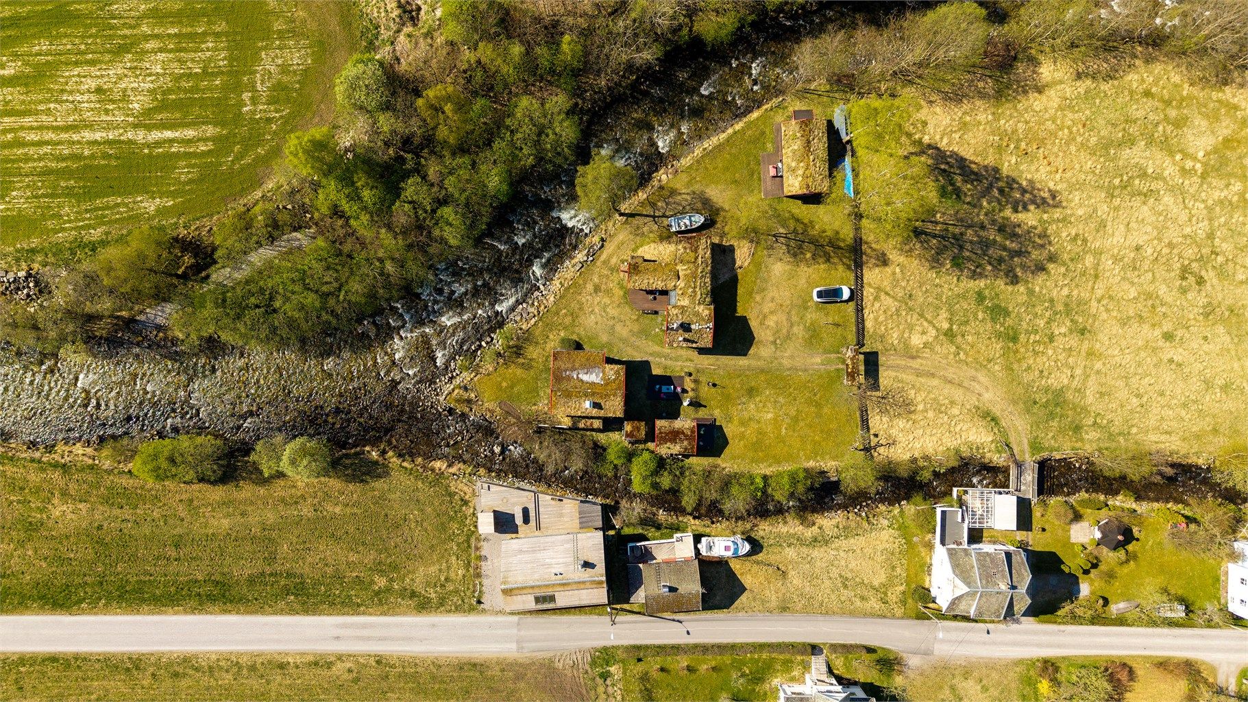 Oversiktsbilde som viser eiendommens unike plassering i landskapet, som et delta i elven.