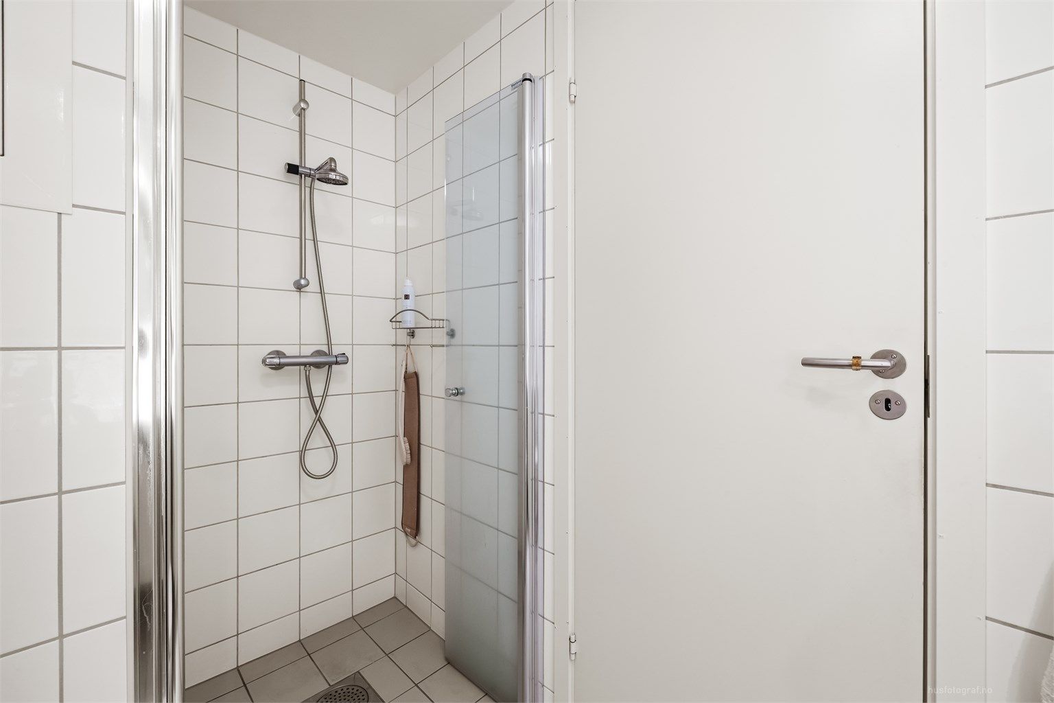 Badet har dusjnisje med innfellbare dører av glass.