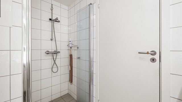 Badet har dusjnisje med innfellbare dører av glass.