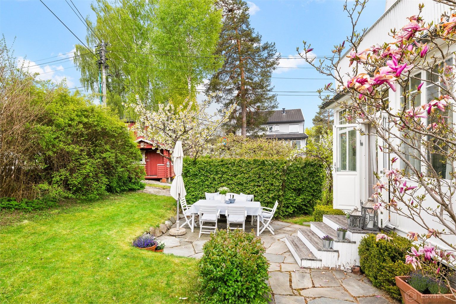 Den skiferbelagte uteplassen ligger i direkte tilknytning til stuen. Legg merke til det vakre Magnolia treet.