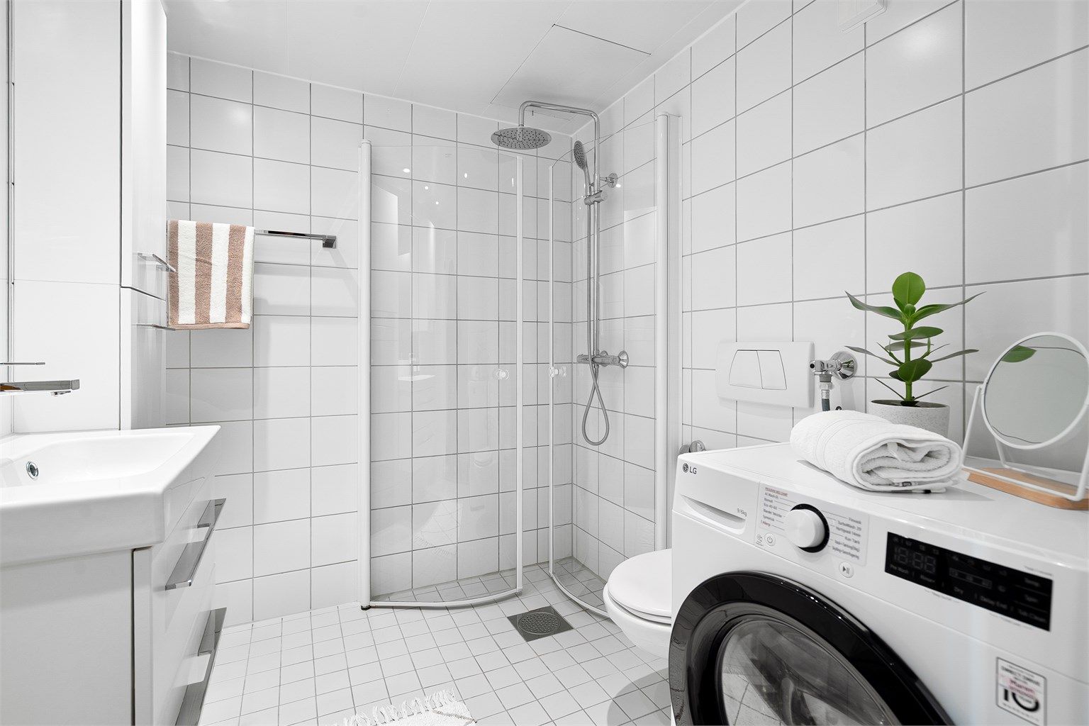 Baderom fra byggeår med opplegg for vaskemaskin, flislagte gulvflater med gulvvarme, flislagte vegger og samt nedsenket himling med downlights.
