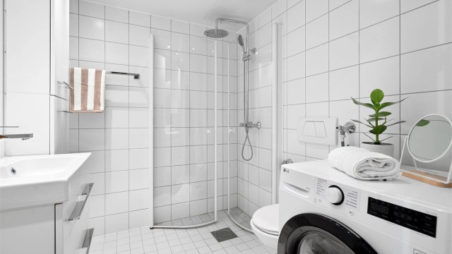 Baderom fra byggeår med opplegg for vaskemaskin, flislagte gulvflater med gulvvarme, flislagte vegger og samt nedsenket himling med downlights.