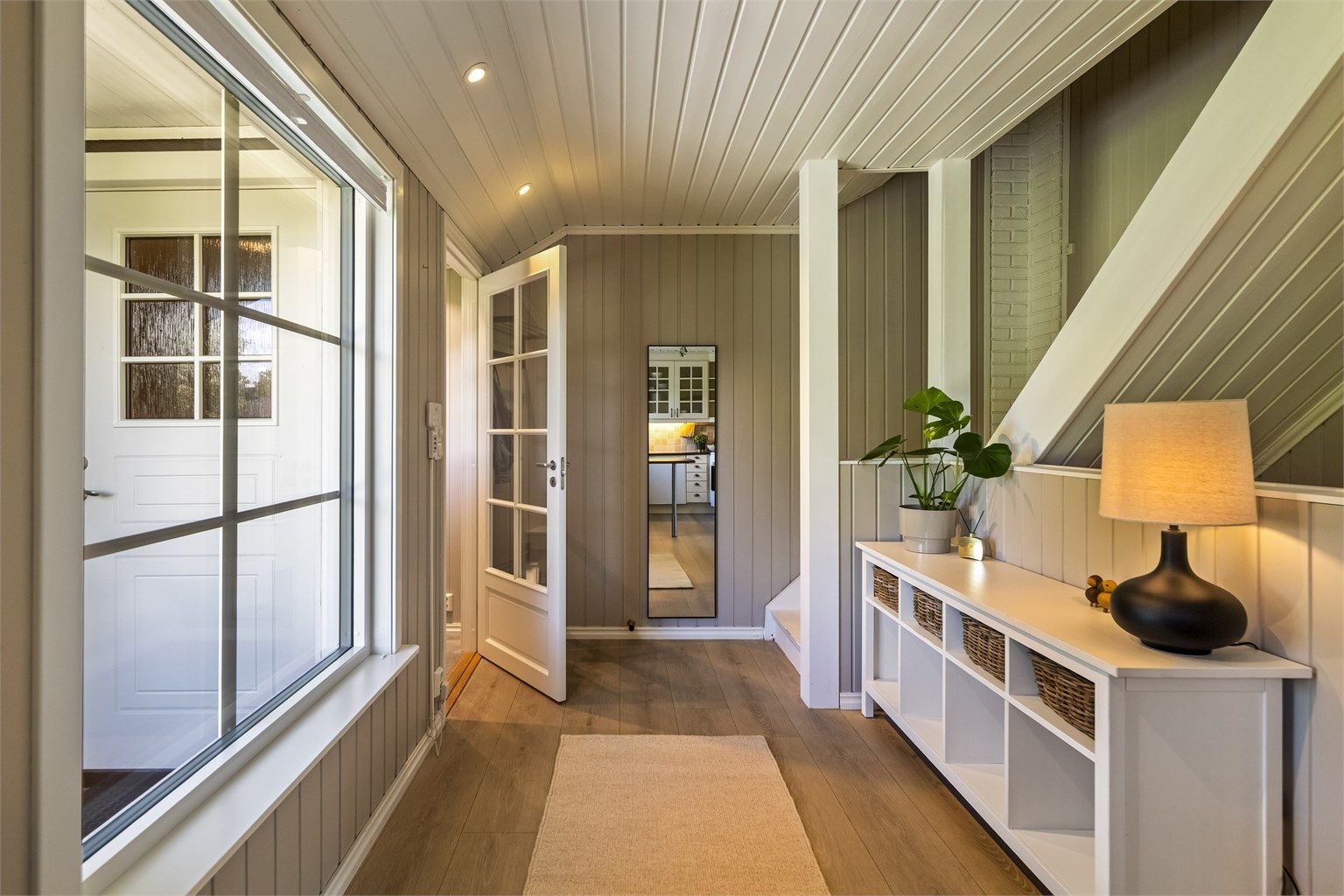 Gangen har innfelte downlights og leder videre inn til kjøkken og stue.