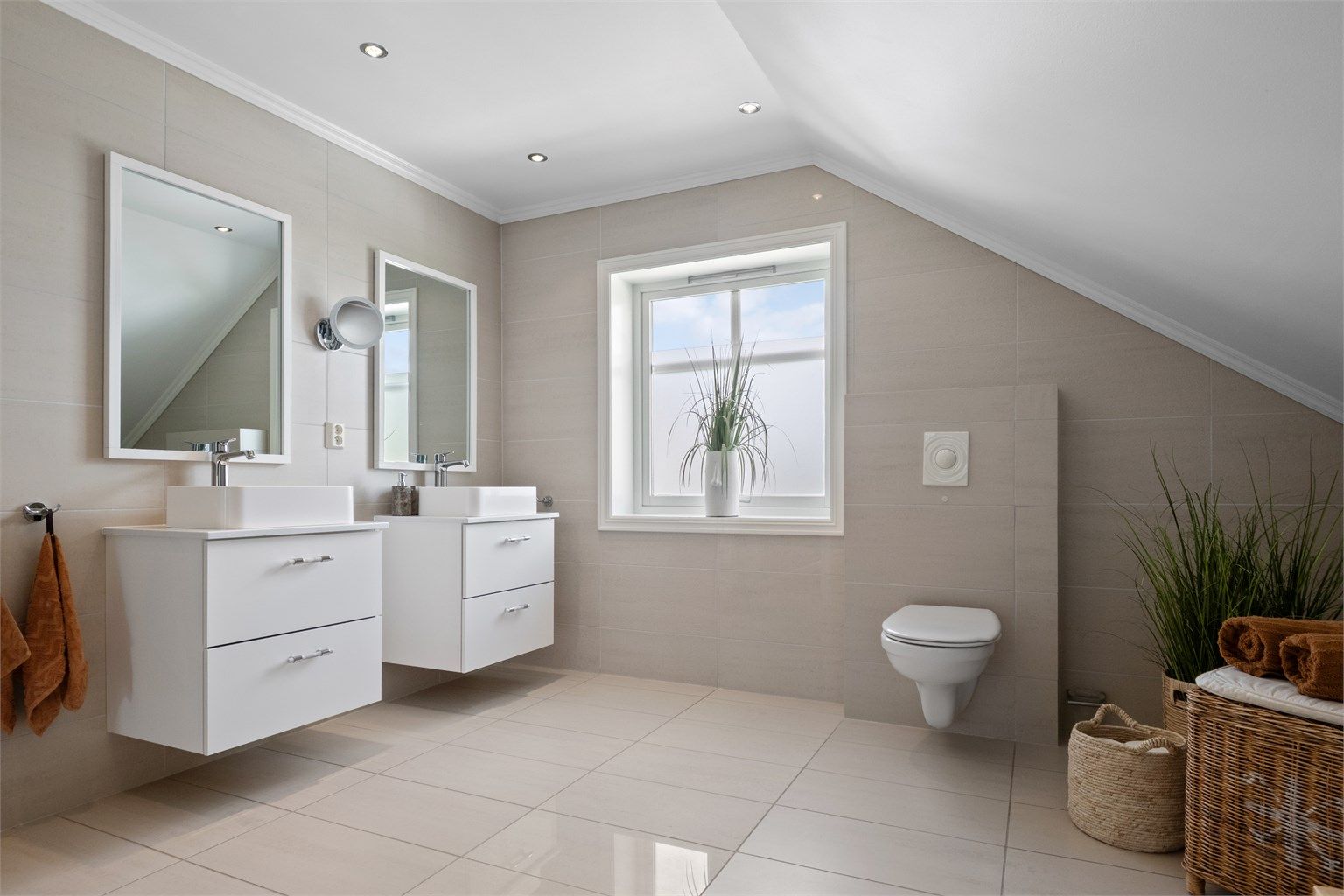 Badet i 2. etasje er romslig og stilrent, med store beige fliser på vegg og gulv.