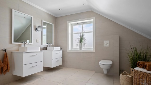 Badet i 2. etasje er romslig og stilrent, med store beige fliser på vegg og gulv.