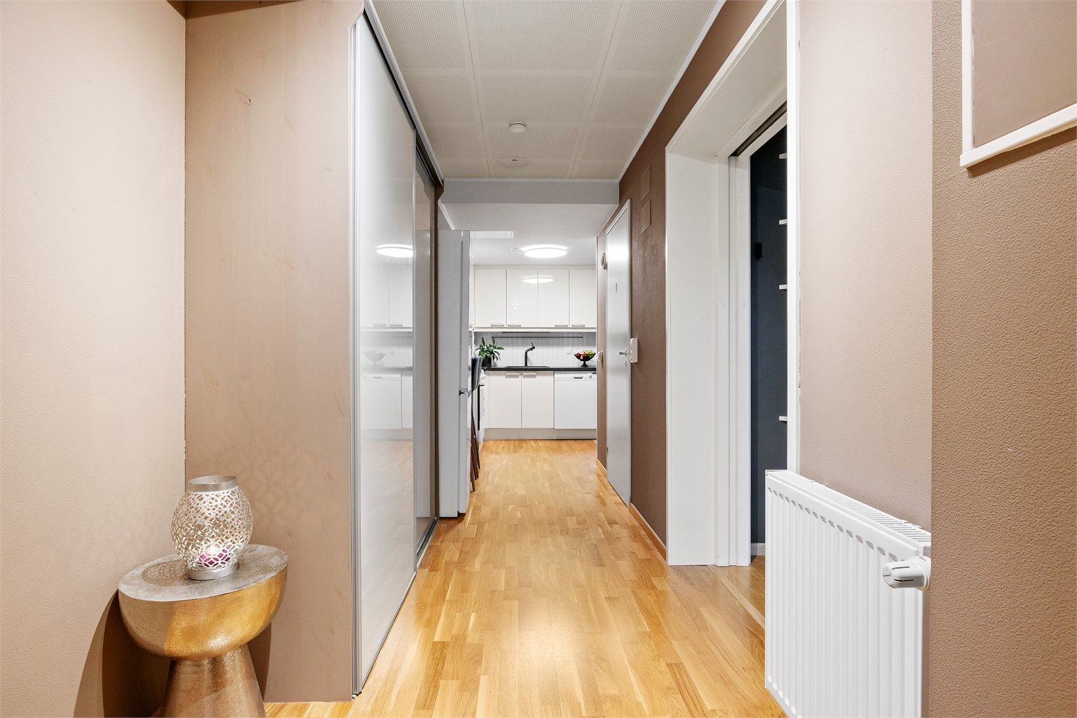 Velkommen inn i en romslig entré med skyvedørsgarderobe