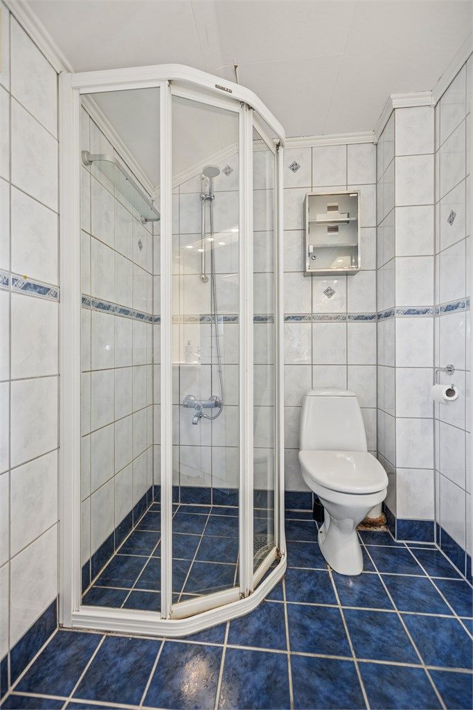 Badet inneholder dusjhjørne, toalett og servantinnredning.