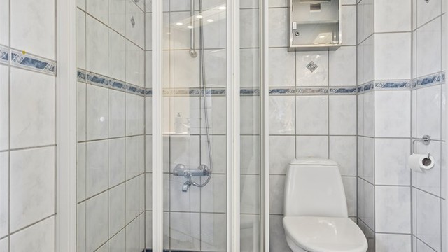 Badet inneholder dusjhjørne, toalett og servantinnredning.