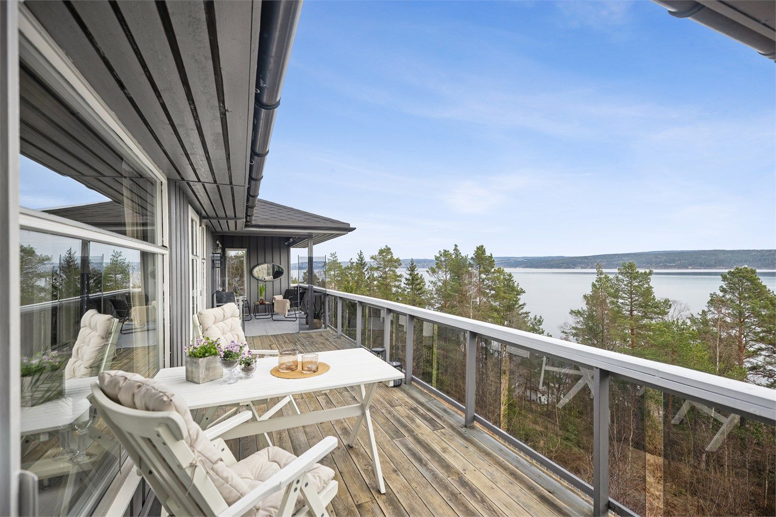 Stor og flott veranda med gode møbleringsmuligheter og en vidstrakt fjordutsikt. Her er alt lagt til rette for å tilbringe sommerhalvåret utendørs.